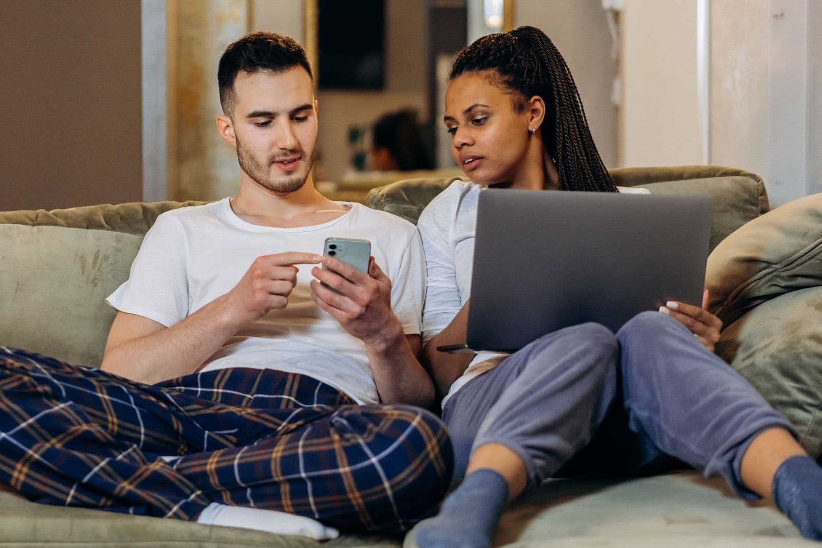 A couple relaxing on the couch at home with a laptop and a phone